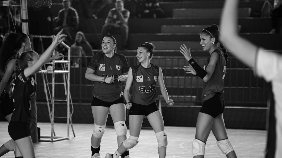 Black and white photo of a female volleyball team celebrating after a successful game.